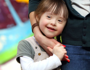 A young girl with Down syndrome is having fun with her mom.